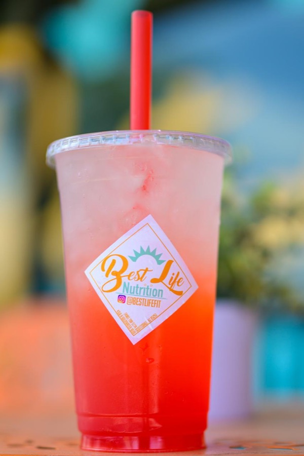 A red and pink layered iced drink in a Best Life Nutrition cup